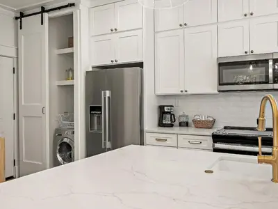 a kitchen with white cabinets and a stainless steel refrigerator at Elegant 5BR 30A Home w Hot tub & Pool in Santa Rosa Beach