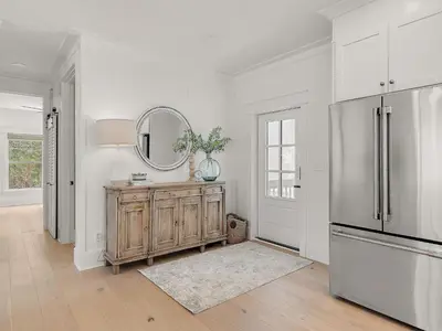 a kitchen with a refrigerator and a mirror on the wall at Elegant 5BR 30A Home w Hot tub & Pool in Santa Rosa Beach