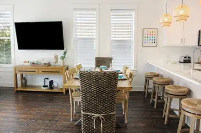 a kitchen and dining room with a table and a tv at Sea La Vie on 30A in Rosemary Beach