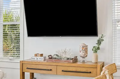 a flat screen tv on a wall above a wooden table at Sea La Vie on 30A in Rosemary Beach