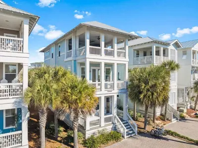 a house with palm trees in front of it at Sea La Vie on 30A in Rosemary Beach