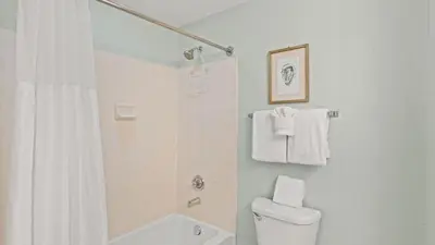 a white bathroom with a shower and a toilet at Beachfront Tidewater Resort Condo w Pools Hot Tubs Pier Park Nearby Tidewater Beach by AvantStay in Panama City Beach