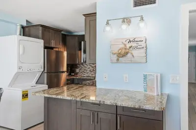 a kitchen with a refrigerator and a counter top at The Summit 922 - Relaxation meets the Shoreline in Panama City Beach