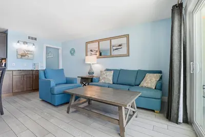 a living room with two blue chairs and a table at The Summit 922 - Relaxation meets the Shoreline in Panama City Beach