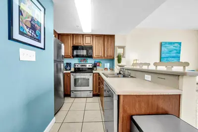 a kitchen with wooden cabinets and stainless steel appliances at Seychelles 602 by Emerald Coast Retreats in Panama City Beach