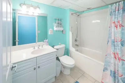 a bathroom with a white toilet and a sink and a shower at Emerald Beach 1628 by Emerald Coast Retreats in Panama City Beach