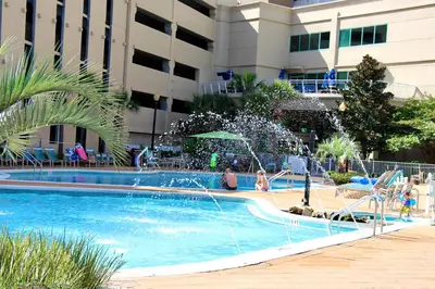 a swimming pool with a fountain in front of a building at Emerald Beach 1628 by Emerald Coast Retreats in Panama City Beach