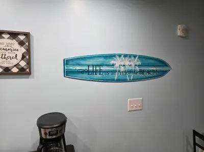 a surfboard hanging on a wall in a room at Beautiful gulf front condo with grill on balcony in Panama City Beach