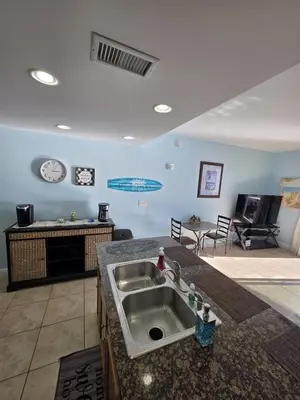a kitchen with a sink and a living room at Beautiful gulf front condo with grill on balcony in Panama City Beach