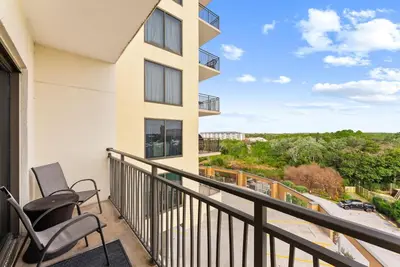 a balcony with two chairs and a view of a street at Origin 0525 - Studio King - Peaceful Nature View in Panama City Beach