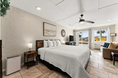 a bedroom with a bed and a living room at The Ambassador - Unit C5 - Studio King - On Pool Deck in Panama City Beach