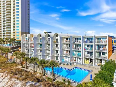 an apartment building with a swimming pool and palm trees at The Ambassador - Unit C5 - Studio King - On Pool Deck in Panama City Beach