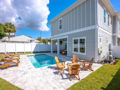 a backyard with a pool and chairs and a house at Coastal Breeze in Panama City Beach