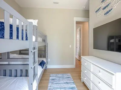 a bedroom with two bunk beds and a tv at Coastal Breeze in Panama City Beach