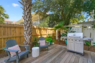 a backyard with a grill and two chairs and a table at Driftwood - Vacation Home Near the Beach with a Large Outdoor Area in Santa Rosa Beach