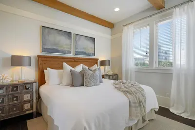 a bedroom with a white bed and two windows at Driftwood - Vacation Home Near the Beach with a Large Outdoor Area in Santa Rosa Beach