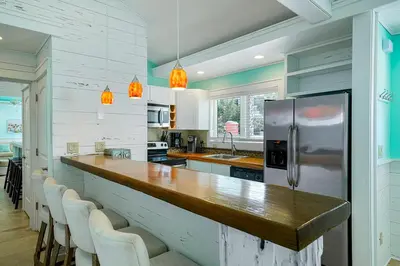 a kitchen with a long counter and a refrigerator at Gulf Escape - 30A Beach House Near the Beach with a Large Pool Space in Inlet Beach