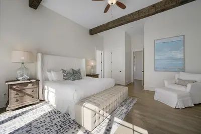 a white bedroom with a bed and a chair at Hermosa Manor - Luxury Vacation Rental House Near the Beach with Private Pool Area & Gulf Views in Santa Rosa Beach