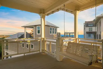 a porch of a house with a swing at Hermosa Manor - Luxury Vacation Rental House Near the Beach with Private Pool Area & Gulf Views in Santa Rosa Beach