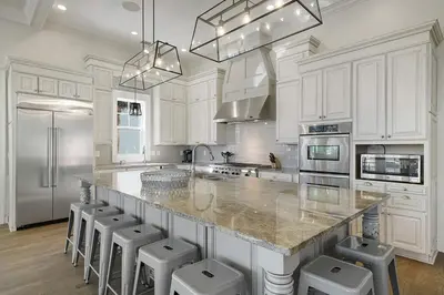 a kitchen with white cabinets and a large island with stools at Hermosa Manor - Luxury Vacation Rental House Near the Beach with Private Pool Area & Gulf Views in Santa Rosa Beach