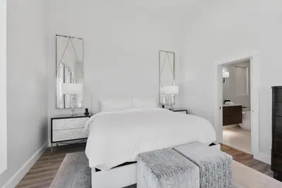a white bedroom with a large bed and a stool at Sea Grove - Beachfront, Ocean Views & Balcony in Santa Rosa Beach
