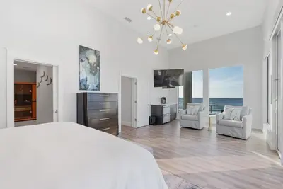 a white bedroom with a bed and two chairs at Sea Grove - Beachfront, Ocean Views & Balcony in Santa Rosa Beach