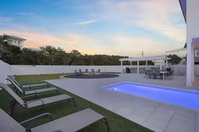 a backyard with a pool and chairs and a table at Inlet Getaway - Luxury Vacation Rental Near the Beach with Private Pool Area & Gulf Views in Seacrest