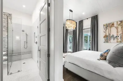a white bedroom with a shower and a bed at YOLO Cottage in Rosemary Beach