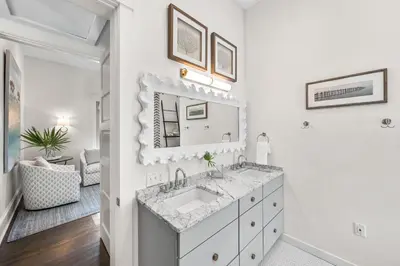 a white bathroom with a sink and a mirror at YOLO Cottage in Rosemary Beach
