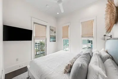 a white bedroom with a large bed and windows at YOLO Cottage in Rosemary Beach