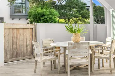 a patio with a table and chairs and a fence at YOLO Cottage in Rosemary Beach