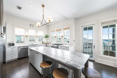 a kitchen with a large island with stools at YOLO Cottage in Rosemary Beach
