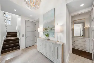 a hallway with white walls and a staircase with a mirror at YOLO Cottage & Carriage in Rosemary Beach
