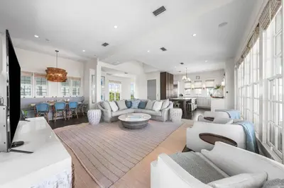 a living room with white furniture and a kitchen at YOLO Cottage & Carriage in Rosemary Beach