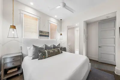 a white bedroom with a large white bed with pillows at YOLO Cottage & Carriage in Rosemary Beach