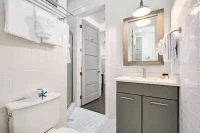 a bathroom with a toilet and a sink and a mirror at YOLO Cottage & Carriage in Rosemary Beach