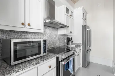 a kitchen with white cabinets and a microwave at YOLO Cottage & Carriage in Rosemary Beach