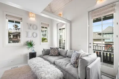 a living room with a couch and windows at YOLO Cottage & Carriage in Rosemary Beach