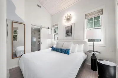 a white bedroom with a large bed and a mirror at YOLO Carriage in Rosemary Beach