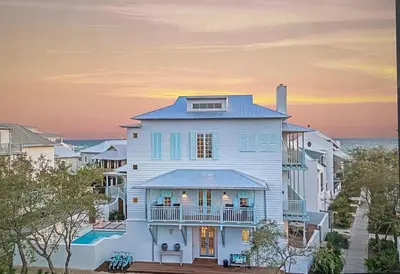 a large white house with the ocean in the background at YOLO Carriage in Rosemary Beach