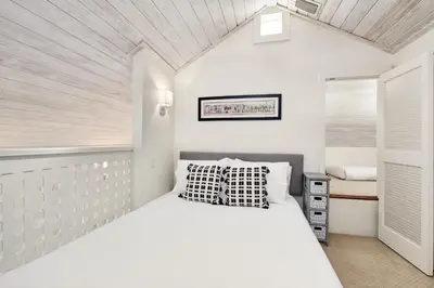 a white bedroom with a bed and a window at YOLO Carriage in Rosemary Beach