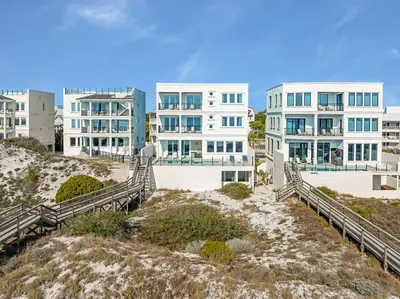 a couple of white buildings on top of a beach at Restoration Point in Santa Rosa Beach