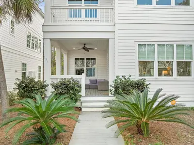 a white house with palm trees in front of it at 30A Pet Friendly Beach House - Scissortrail at Treetops in Seacrest