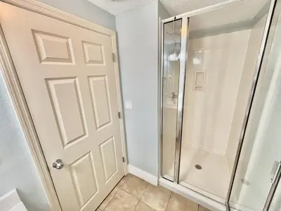 a bathroom with a shower and a glass door at Beachfront Studio with Bunks Sleeps 4 at Majestic! in Panama City Beach
