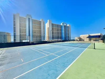 a tennis court in front of a city with tall buildings at Beachfront Studio with Bunks Sleeps 4 at Majestic! in Panama City Beach