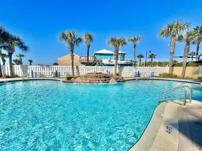 a large swimming pool with palm trees in a resort at Beachfront Studio with Bunks Sleeps 4 at Majestic! in Panama City Beach