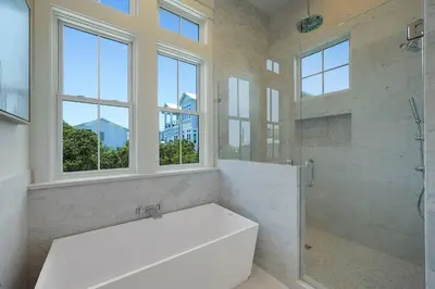 a bathroom with a white tub and a shower with windows at Pompano Paradise - 30A Vacation House with Ocean Views, Private Pool & Golf Cart in Rosemary Beach