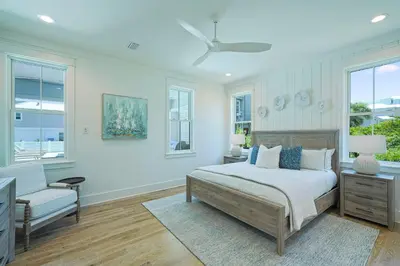 a bedroom with a bed and a chair and windows at Pompano Paradise - 30A Vacation House with Ocean Views, Private Pool & Golf Cart in Rosemary Beach