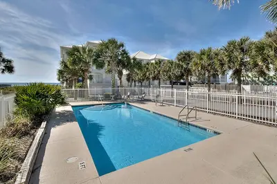 a swimming pool with palm trees and a fence at Seaview 1 Unit 300 - Gulf Front Condo on 30A & Ocean Views in Santa Rosa Beach