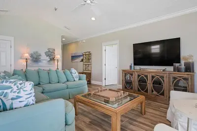 a living room with a blue couch and a tv at Seaview 1 Unit 300 - Gulf Front Condo on 30A & Ocean Views in Santa Rosa Beach